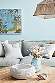 Coffee table with bowl and vase in front of light grey upholstered sofa