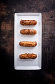 Fried duck sausages (India) on a serving platter against a dark background