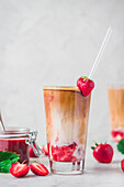 Iced Flat White mit Erdbeere und Erdbeersauce serviert im Glas