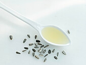 Sunflower oil on spoon next to unshelled sunflower seeds