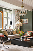 Mixed styles in the living room with coffered walls in dark green