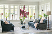 Coffee table with flowers and grey velvet sofas in bright living room