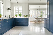 Cabinets with blue fronts in kitchen with white-painted wood panelling