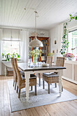 Dining table and rattan chairs in bright room with wooden floorboards