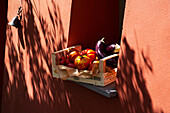 Kiste mit frisch geernteten Auberginen und Tomaten in Fensternische