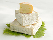 Three different French cheeses stacked on a vine leaf