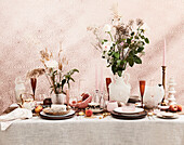 Gedeckter Tisch in Rosa und Pfirsichtönen, Blumensträuße und Kerzen