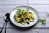Pasta with spinach pesto, carrots, spinach leaves and pine nuts