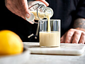 Ingwer-Shot mit Zitrone wird in Glas gegossen