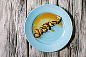 Smoked mussels in oil on blue ceramic plate