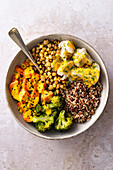 A bowl filles with vegetables and quinoa, drizzled with turmeric tahini sauce