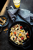 Sage and Tomato casarecce Pasta in a skillet against a dark background