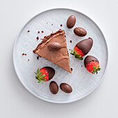A slice of chocolate cheesecake with chocolate-dipped strawberries