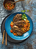 Spicy Pork Neck Chop in a blue bowl with beans