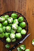 Brusssel sprouts in a wire basket on a wooden textured background