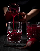 Frisch gepressten Rote-Bete-Saft in ein dekoratives Glas giessen