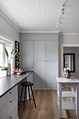 Light grey fitted furniture and table in pale kitchen with wood panelling