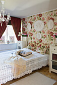Romantisches Schlafzimmer mit Rosentapeten, Gipsreliefs und gehäkelter Tagesdecken
