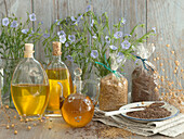 Three bottles of linseed oil, golden and brown linseed oil seeds, and linseed flowers