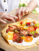 Making a tomato galette as hands fold down the edge of the pastry