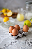 Fresh eggs in an egg carton, lemons, a lemon squeezer and lemon juice