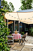 Round table and wooden chairs under awning on terrace