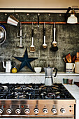 Espresso pot on gas stove below kitchen utensils on wall
