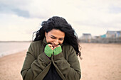 Happy woman in winter coat on beach