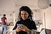 Happy woman using smart phone at home