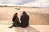 Couple in winter coats on sunny beach