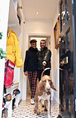 Gay male couple leaving house to walk dog