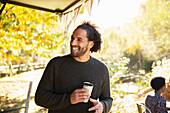 Happy man with coffee in sunny autumn park