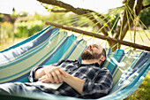 Serene man relaxing in sunny summer hammock