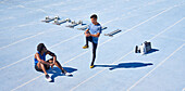 Young male runners on sunny blue sports track