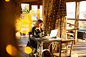 Businesswoman working on laptop in sunny cafe