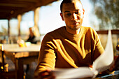 Businessman reviewing paperwork in sunny cafe