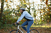 Happy young man riding bicycle in autumn park