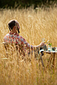 Man relaxing at table in sunny summer tall grass