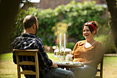 Happy couple enjoying cake at summer garden table