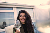 Happy carefree woman enjoying white wine on patio