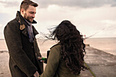 Affectionate couple in winter coats on beach jetty