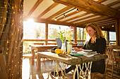 Businesswoman working on laptop in sunny restaurant
