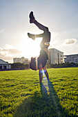 Carefree young man doing handstand in sunny park