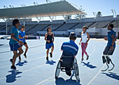 Athletes warming up on sunny blue sports track