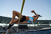 Female track and field athlete high jumping over pole