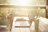 Headphones, laptop and coffee on sunny cafe table