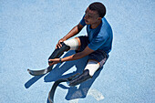 Male amputee sprinter preparing on blue sports track