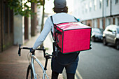 Male bike messenger delivering food on urban sidewalk