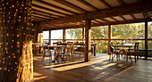 Wooden tables and chairs in sunny empty restaurant