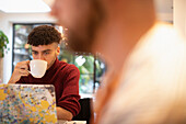 Young man drinking coffee working from home on laptop